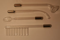 A picture of the four glass attachments or probes that come with our solid state violet wand kit. The four shapes are: mushroom head, curved ball point, spoon, comb.