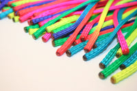 Rainbow & Tye Dye colored paracord flogger with 60 BB weighted falls. Closeup detail of the tips of the falls. Stuffed with metal BB's and melted shut.